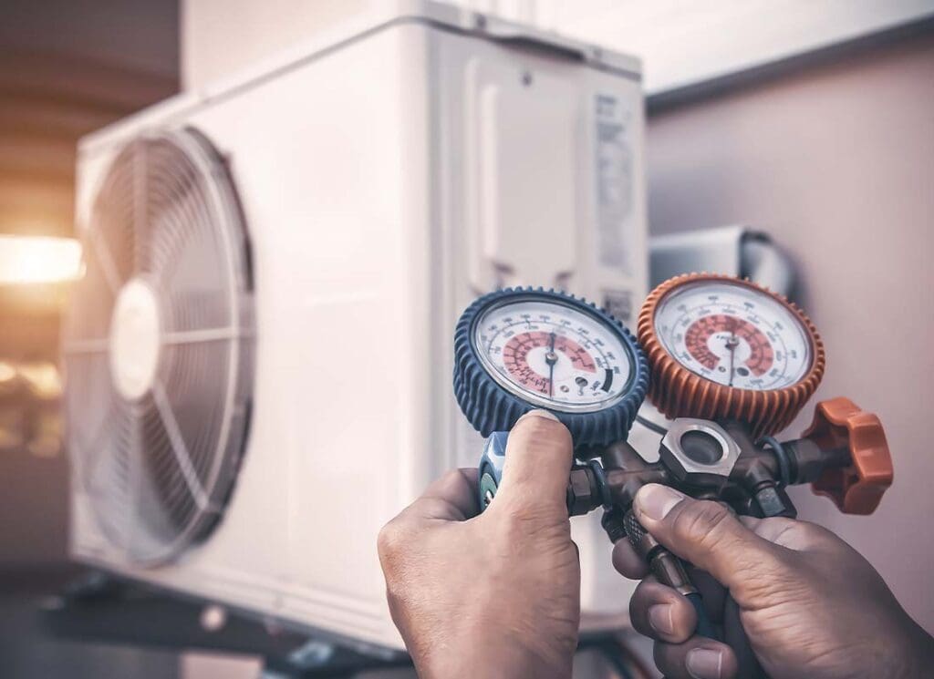HVAC Contractor Insurance - HVAC Mechanic Using Pressure Gauge Equipment for Home Air Conditioner After Maintenance and Checking Outdoor Air Compressor Unit